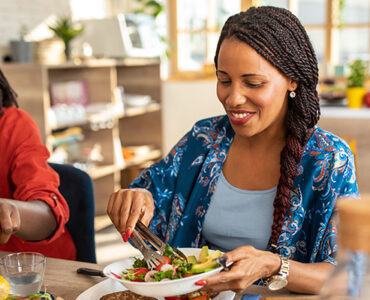 Two women sitting at the table together, eating healthy whole and plant-based foods.