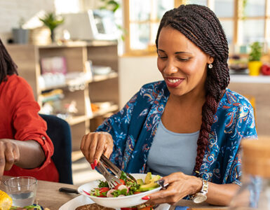 Two women sitting at the table together, eating healthy whole and plant-based foods.