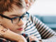 A boy sits with his mother on their living room couch, looking over online resources about transgender youth support.