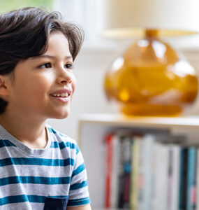 A boy sitting down and looking at his mother, who is noticing his involuntary movements, or tics.