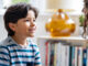 A boy sitting down and looking at his mother, who is noticing his involuntary movements, or tics.