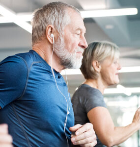 A group of older adults exercising on treadmills next to one another, as part of their cardiac rehab program.