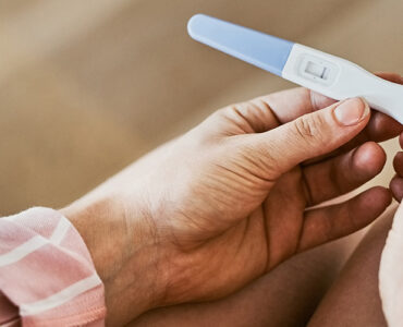 The hands of a woman looking at a negative result on her pregnant result.