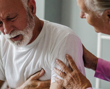 A man experiencing chest pain and shortness of breath, with his wife concerned about him.