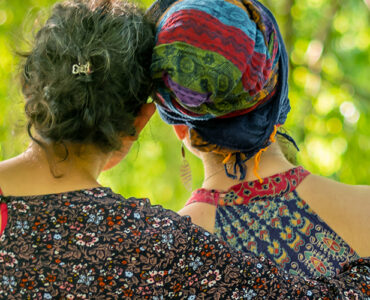 Two friends hugging while sitting outside.