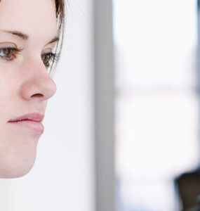 A teenage girl weighing herself on a scale, looking at the results with a frown on her face.