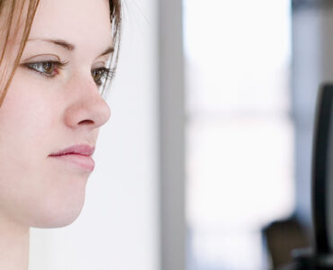 A teenage girl weighing herself on a scale, looking at the results with a frown on her face.