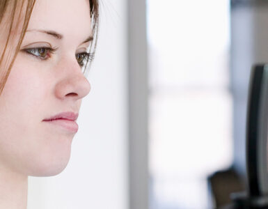 A teenage girl weighing herself on a scale, looking at the results with a frown on her face.