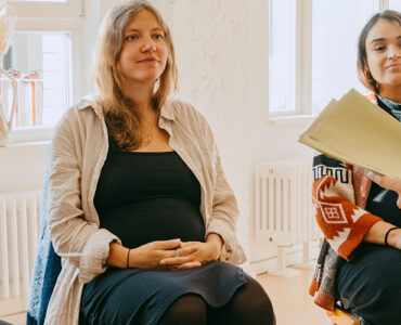 A group of pregnant women sitting in a circle, receiving group support from their midwife.