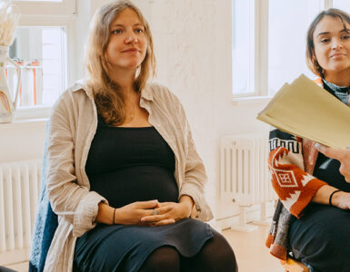 A group of pregnant women sitting in a circle, receiving group support from their midwife.