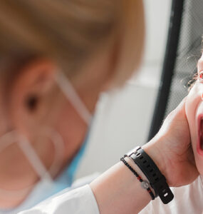 A young girl with a mouth rash being evaluated by her female doctor.