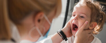 A young girl with a mouth rash being evaluated by her female doctor.