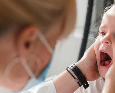 A young girl with a mouth rash being evaluated by her female doctor.