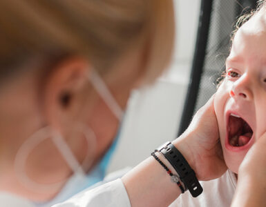 A young girl with a mouth rash being evaluated by her female doctor.