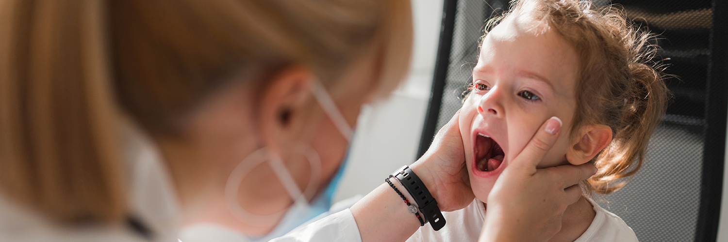A young girl with a mouth rash being evaluated by her female doctor.