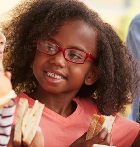 Kids sitting in the school cafeteria, eating lunch together.