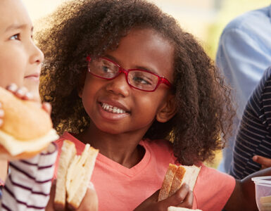 Kids sitting in the school cafeteria, eating lunch together.