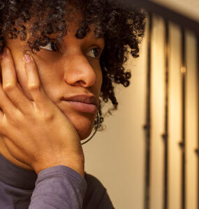 Woman sitting at her desk, looking away and distracted.