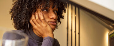 Woman sitting at her desk, looking away and distracted.