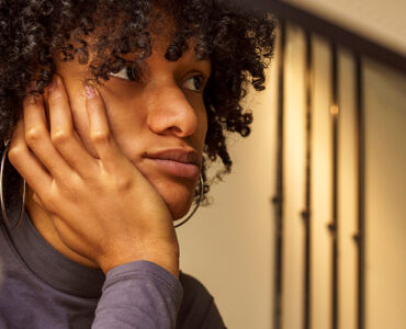 Woman sitting at her desk, looking away and distracted.