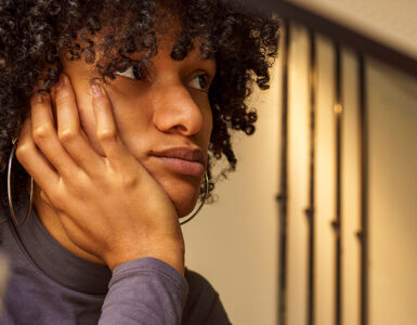 Woman sitting at her desk, looking away and distracted.