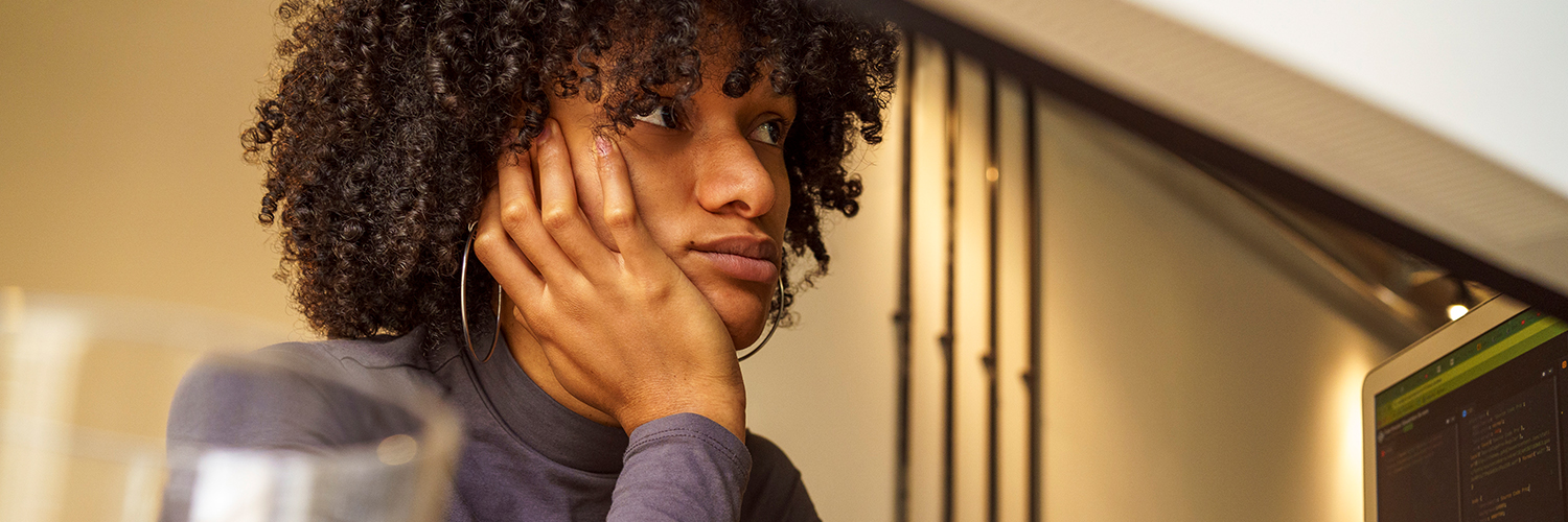Woman sitting at her desk, looking away and distracted.