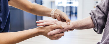 An older woman having her hand and wrist examined by an orthopedist because of pain.