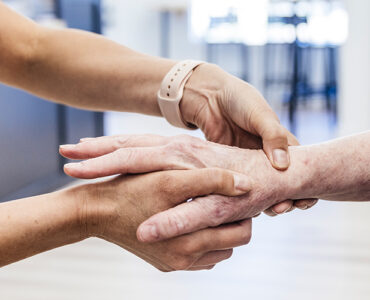 An older woman having her hand and wrist examined by an orthopedist because of pain.