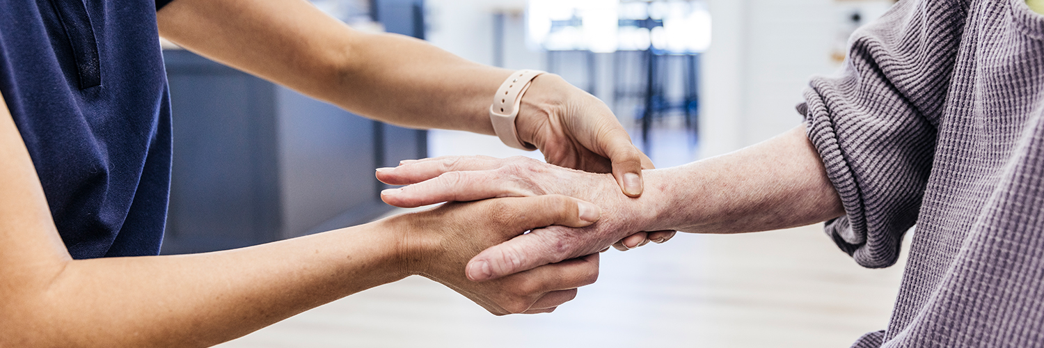 An older woman having her hand and wrist examined by an orthopedist because of pain.