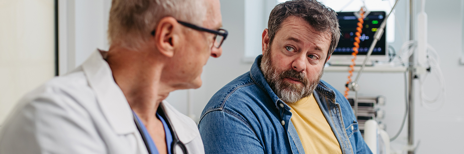 An overweight and middle-aged man sitting with his doctor to review his medical report.