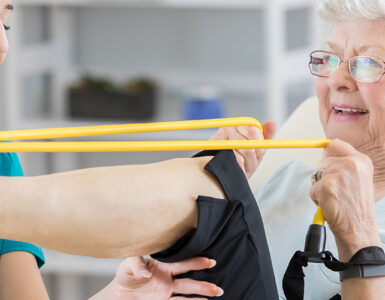 A senior woman stretching her leg alongside her female physical therapist.