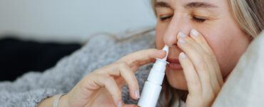 A young women on her couch, using a nasal stick for decongesting her nose.
