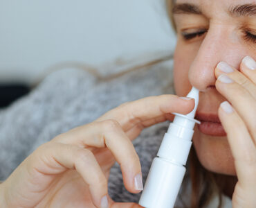 A young women on her couch, using a nasal stick for decongesting her nose.