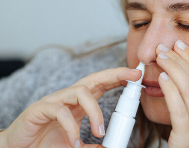 A young women on her couch, using a nasal stick for decongesting her nose.