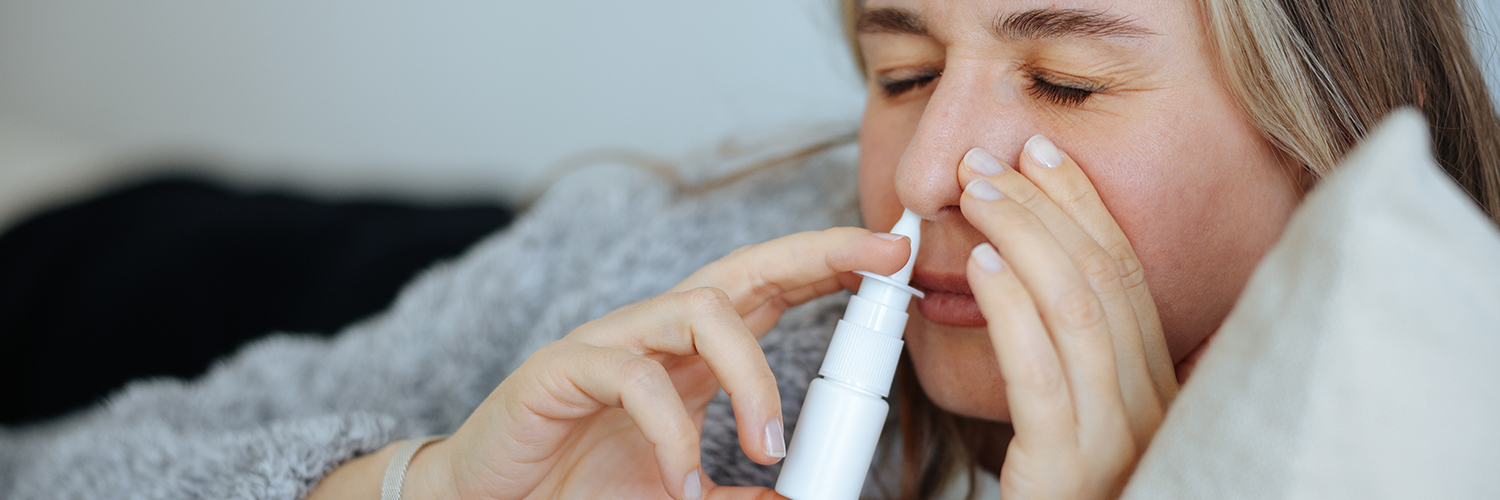 A young women on her couch, using a nasal stick for decongesting her nose.