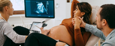A pregnant woman holding her husband's hand while getting an ultrasound.