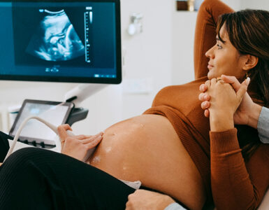 A pregnant woman holding her husband's hand while getting an ultrasound.