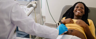 A pregnant woman smiling as she gets a special test called a fetal echo ultrasound in her doctor's office.