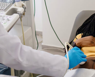 A pregnant woman smiling as she gets a special test called a fetal echo ultrasound in her doctor's office.