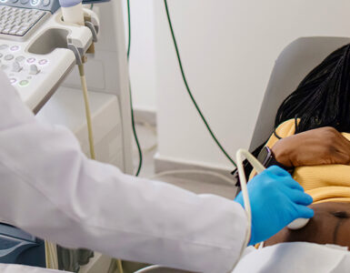 A pregnant woman smiling as she gets a special test called a fetal echo ultrasound in her doctor's office.