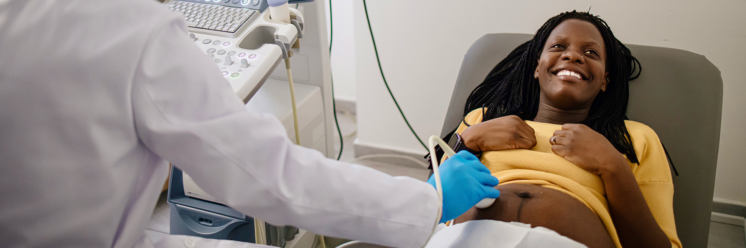 A pregnant woman smiling as she gets a special test called a fetal echo ultrasound in her doctor's office.