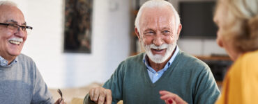 A group of older adults sitting together at a dining table, laughing.