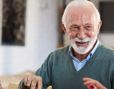 A group of older adults sitting together at a dining table, laughing.