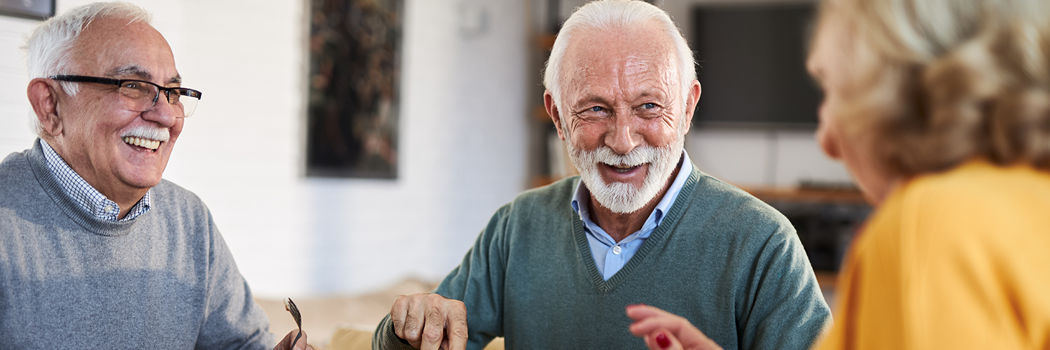 A group of older adults sitting together at a dining table, laughing.