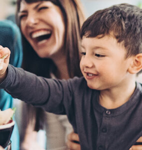 A family working together to prepare a salad, with a little boy helping and smiling.