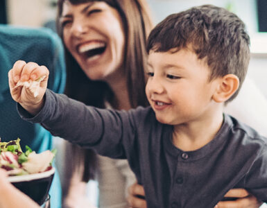 A family working together to prepare a salad, with a little boy helping and smiling.