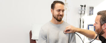 A young male patient sitting with his doctor in a medical office.