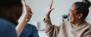 A black middle-aged woman giving her oncologist a high five while smiling.