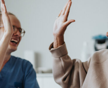 A black middle-aged woman giving her oncologist a high five while smiling.