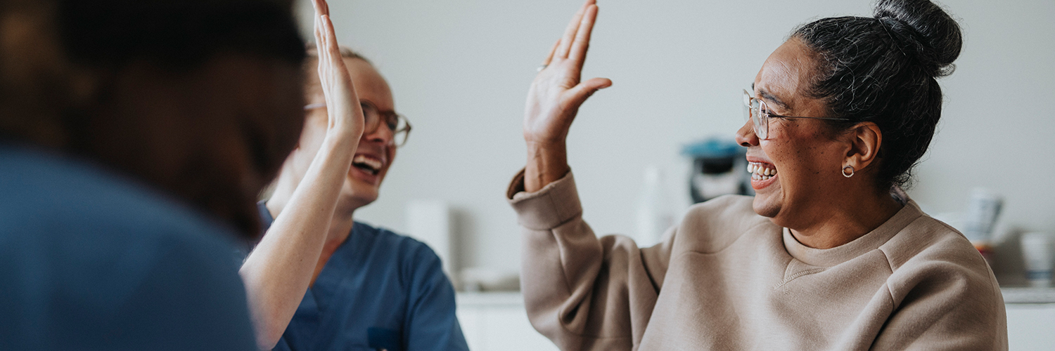 A black middle-aged woman giving her oncologist a high five while smiling.